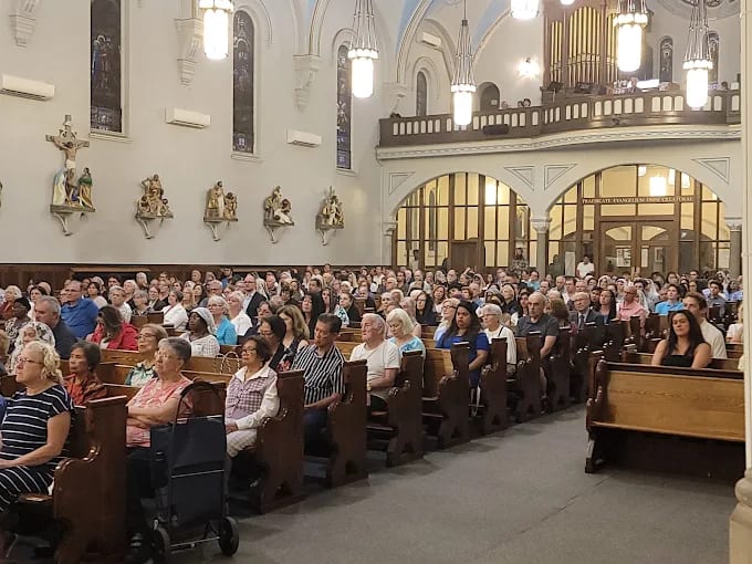 A full congregation in the pews of St. Ann's, with the organ gallery behind
